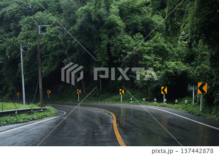 Winding mountain road passes through lush tropical forest on a rainy day in Thailand 137442878