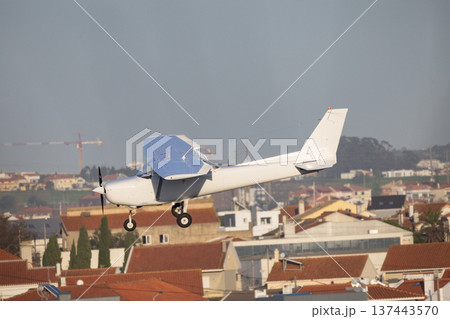 Small private plane flying low over city houses 137443570