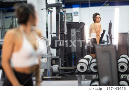 Woman posing in gym mirror showing muscular back 137443626
