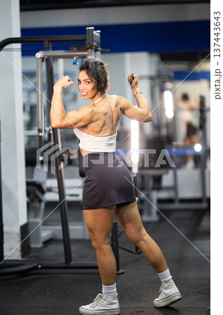 Strong woman flexing muscles showing back and bicep definition Strong woman flexing muscles showing back and bicep definition 137443643