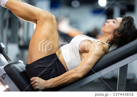 Woman exercising legs on gym leg press machine 137443658