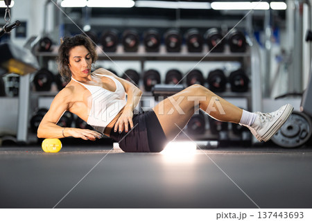 Woman massaging muscles with foam rollers in gym Woman massaging muscles with foam rollers in gym 137443693