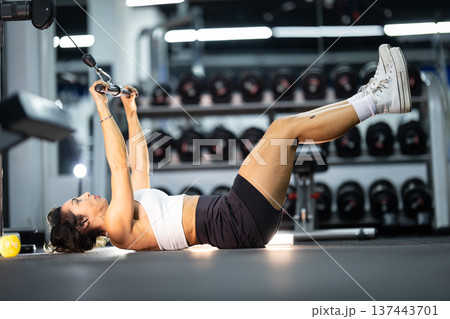 Woman exercising core strength with cable machine in gym 137443701