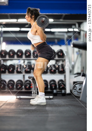 Woman squatting with barbell training leg strength in gym Woman squatting with barbell training leg strength in gym 137443715