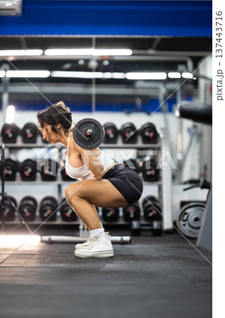 Woman doing barbell squats during gym workout Woman doing barbell squats during gym workout 137443716