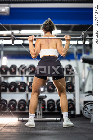 Strong woman performing barbell squats in modern gym Strong woman performing barbell squats in modern gym 137443721