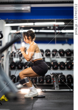 Fit woman strengthening legs with cable workout in gym Fit woman strengthening legs with cable workout in gym 137443722