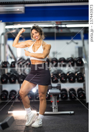 Confident woman flexing bicep showing gym fitness 137443973