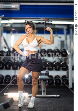 Confident woman flexing biceps showing strength in gym 137443981