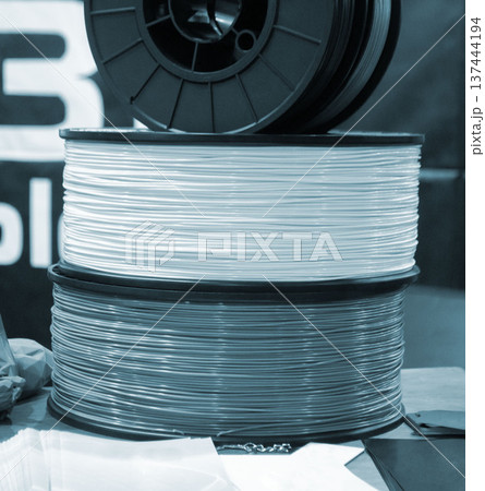 Spool of plastic wire for 3D printing. Spool with white plastic close-up. Component for 3d printing. Printing accessories. Concept modern 3D printing technology. Additive progressive FDM technologies Spool of plastic wire for 3D printing. Spool with white plastic close-up. Component for 3d printing. Printing accessories. Concept modern 3D printing technology. Additive progressive FDM technologies 137444194