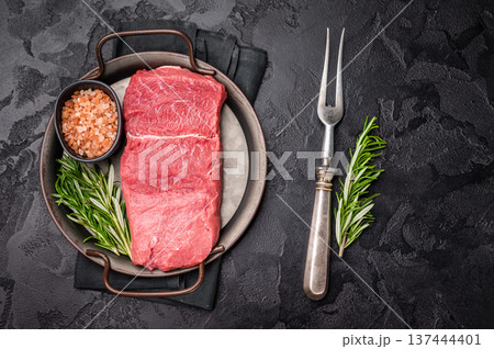 A selection of raw bison steaks arranged artfully, emphasizing their quality and texture, inviting culinary creativity in the kitchen. black background. top view 137444401
