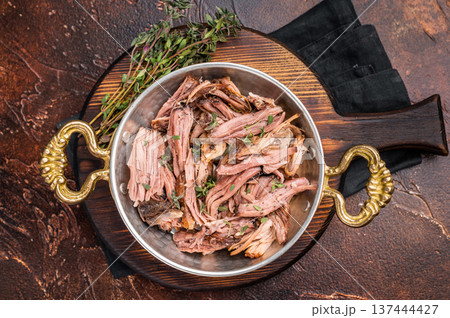 Close-up of succulent pulled brisket piled high on a rustic wooden board, garnished with fresh herbs, delicious meal. brown background. top view Close-up of succulent pulled brisket piled high on a rustic wooden board, garnished with fresh herbs, delicious meal. brown background. top view 137444427