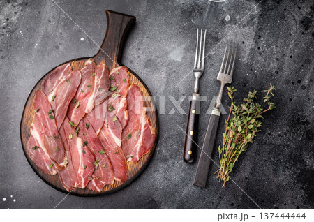 Slovenian ham, sliced cured pork meat on wooden board, Prsut. black background. top view Slovenian ham, sliced cured pork meat on wooden board, Prsut. black background. top view 137444444