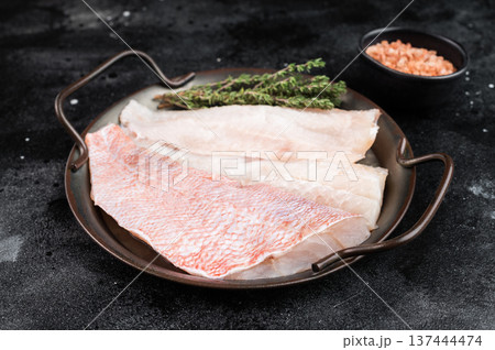 Raw redfish fillets on plate with thyme. Fresh seafood ingredient on dark background with copy space. Raw redfish fillets on plate with thyme. Fresh seafood ingredient on dark background with copy space. 137444474