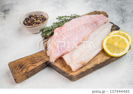 Ocean red perch fish fillets with lemon slices and pepper on cutting board. Fresh marine seafood ingredient for cooking.. 137444485