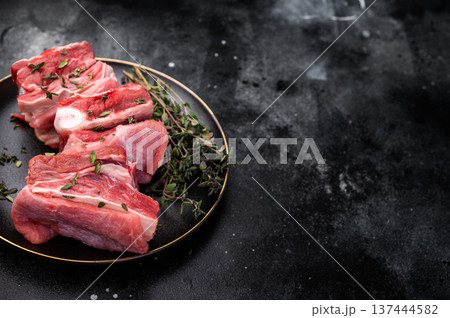 Raw mutton cut rib chops, fresh lamb meat with herbs for grilling. black background. top view Raw mutton cut rib chops, fresh lamb meat with herbs for grilling. black background. top view 137444582