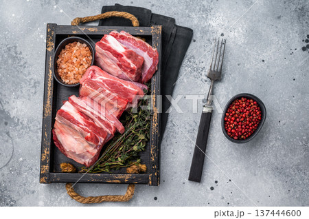 Fresh Raw lamb rib cuts, mutton meat with rib bone in wooden board. grey background. top view Fresh Raw lamb rib cuts, mutton meat with rib bone in wooden board. grey background. top view 137444600