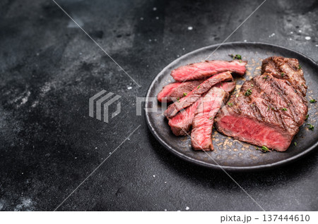 Grilled New York Striploin steak, perfectly seared with beautiful grill marks, showcasing its juicy tenderness and rich flavor. black background. top view 137444610