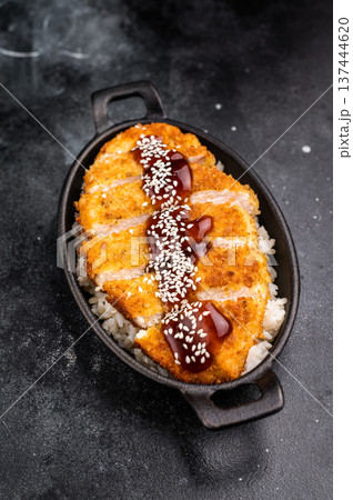 Crunchy Japanese cutlet katsu, seasoned to perfection and served with a side of rice and sauce. black background. top view 137444620