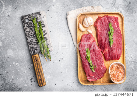 Raw Ostrich steaks, fresh Game Meat in wooden tray. grey background. top view Raw Ostrich steaks, fresh Game Meat in wooden tray. grey background. top view 137444671
