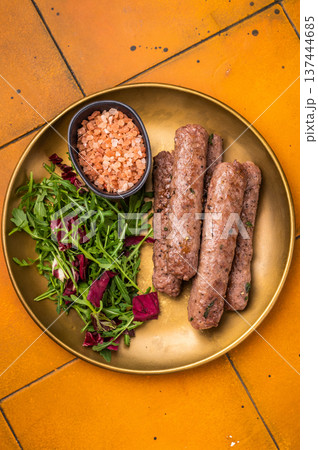 Grilled kofta or lula kebabs from mince lamb and beef meat on a plate with salad. brown background. top view Grilled kofta or lula kebabs from mince lamb and beef meat on a plate with salad. brown background. top view 137444685