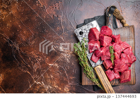 Diced Raw Boar meat, uncooked Game Meat on butcher cutting board. brown background. top view Diced Raw Boar meat, uncooked Game Meat on butcher cutting board. brown background. top view 137444693