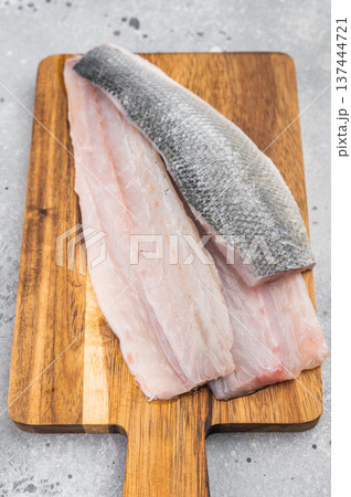 Raw sea bass or seabass fillets with thyme on rustic wooden cutting board, fresh Mediterranean seafood ingredient Raw sea bass or seabass fillets with thyme on rustic wooden cutting board, fresh Mediterranean seafood ingredient 137444721