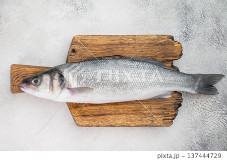 Fresh whole sea bass with thyme and garlic on rustic wooden board over isolated background, Mediterranean seafood ingredient with wide copy space. 137444729
