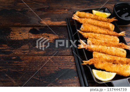 Golden deep fried prawns in panko breadcrumbs, ebifry style seafood appetizer shot from above, crispy asian cuisine finger food on wooden background. Golden deep fried prawns in panko breadcrumbs, ebifry style seafood appetizer shot from above, crispy asian cuisine finger food on wooden background. 137444739