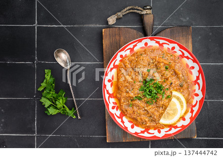 Classic Indian eggplant bharta vegetarian mashed aubergine curry dip served in decorative red plate with lemon garnish dark background food photography Classic Indian eggplant bharta vegetarian mashed aubergine curry dip served in decorative red plate with lemon garnish dark background food photography 137444742