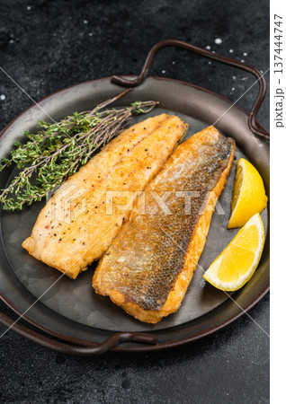 Golden pan fried sea bass or seabass fish fillet plated with thyme and citrus, healthy mediterranean cuisine concept captured in rustic food styling. 137444747