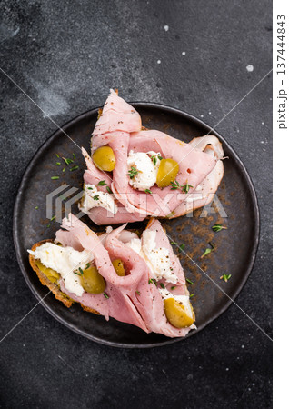 Bruschetta with Prosciutto Cotto ham, burrata mozzarella and olives. black background. top view 137444843