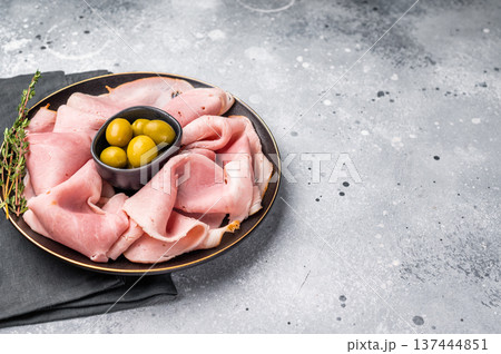 Meat appetizer with Sliced Prosciutto Cotto ham and green olives. grey background. top view 137444851