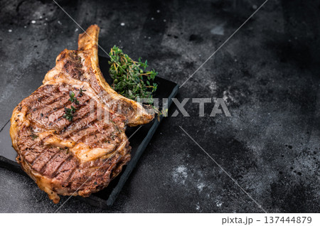 BBQ Grilled Tomahawk beef steak, cooked rib eye with bone on marble board. black background. top view BBQ Grilled Tomahawk beef steak, cooked rib eye with bone on marble board. black background. top view 137444879