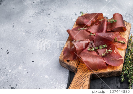 Dried beef meat Cecina, slices of beef jerky on wooden board with herbs. grey background. top view 137444880