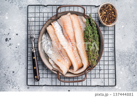 Raw Hake fish fillet in steel tray with herbs. grey background. top view 137444881