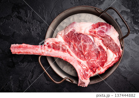 Raw tomahawk steak with marbling, fresh rib eye with bone. black background. top view 137444882
