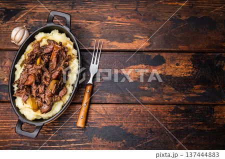 Braised Beef Cheek, Slow cooked meat with smashed potatoes in a skillet. wooden background. top view 137444883