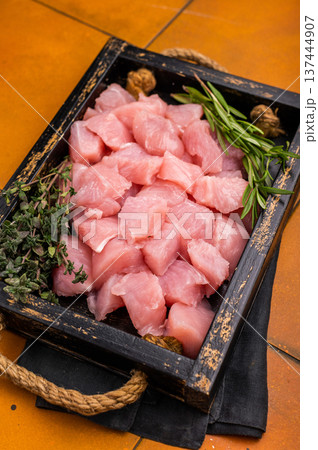Diced sliced chicken fillet cubes, poultry meat with herbs for cooking. orange background. top view Diced sliced chicken fillet cubes, poultry meat with herbs for cooking. orange background. top view 137444907