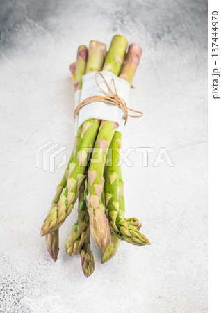 Green asparagus on wooden cutting board with herbs and salt, healthy vegetarian ingredient shot in minimal bright culinary style 137444970