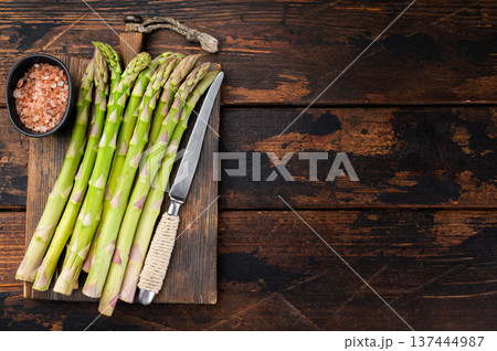 Raw green asparagus bundle on dark wooden background with copy space, healthy vegan ingredient concept in rustic culinary style 137444987