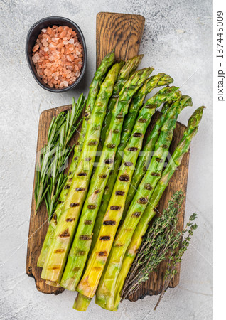 Roasted asparagus vegetable side dish styled with rosemary and thyme on cutting board, minimal healthy food concept, top view 137445009