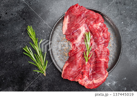 Butcher style raw machete steak also known as skirt on dark textured table with rosemary herb and natural food styling 137445019