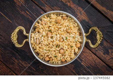 Traditional Turkish bulgur pilav nohutlu with chickpeas and thyme in metal bowl on dark wooden table overhead Traditional Turkish bulgur pilav nohutlu with chickpeas and thyme in metal bowl on dark wooden table overhead 137445082