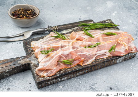 Cured pork belly, streaky bacon slices displayed on rustic wooden board with herbs perfect for stock images culinary design and menu concepts 137445087