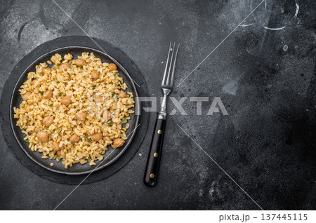 Traditional Turkish bulgur pilav with chickpeas vegan plant based dish on dark textured background overhead 137445115