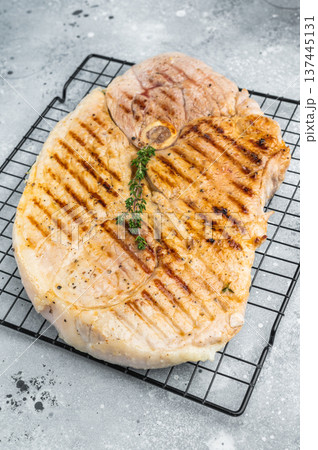 Grilled bone in pork shoulder with herbs on cooling rack cooked meat with grill marks prepared for barbecue and rustic serving Grilled bone in pork shoulder with herbs on cooling rack cooked meat with grill marks prepared for barbecue and rustic serving 137445131