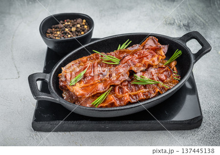 Crispy sizzling bacon with rich smoked pork flavor served in cast iron with rosemary on concrete background perfect for food photography. Crispy sizzling bacon with rich smoked pork flavor served in cast iron with rosemary on concrete background perfect for food photography. 137445138