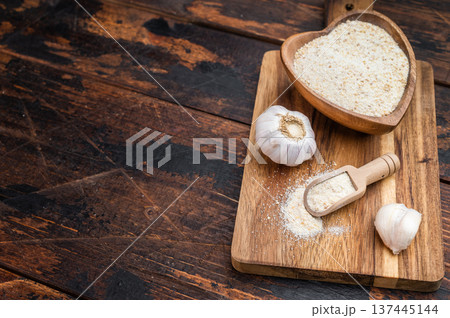 Dried granulated garlic seasoning with fine texture in wooden bowl. Rustic culinary ingredient flatlay background. Dried granulated garlic seasoning with fine texture in wooden bowl. Rustic culinary ingredient flatlay background. 137445144