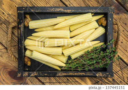 Whole uncooked baby corn in wooden crate on rustic table with thyme flat lay ideal for natural food photography and stock use Whole uncooked baby corn in wooden crate on rustic table with thyme flat lay ideal for natural food photography and stock use 137445151